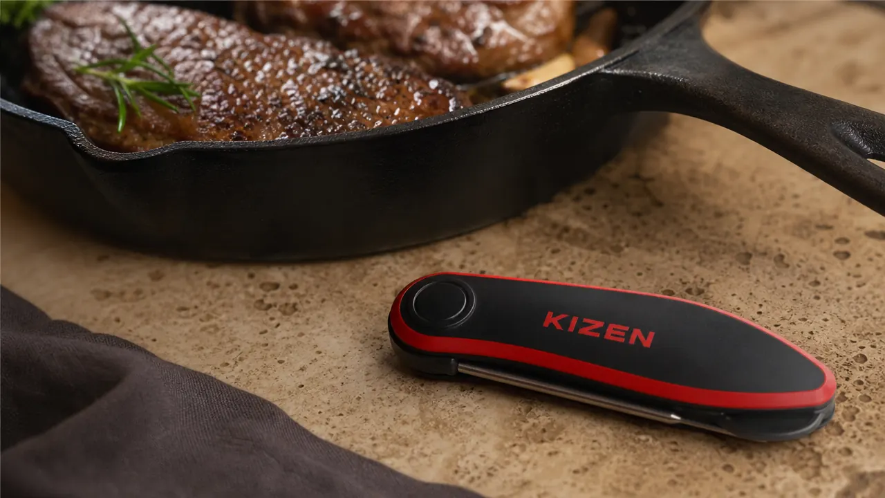 KIZEN thermometer sitting on a kitchen counter next to a cast iron skillet with seared steak